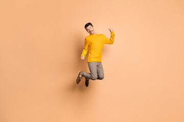 Fototapeta na wymiar Full length photo portrait of excited man jumping up isolated on pastel beige colored background