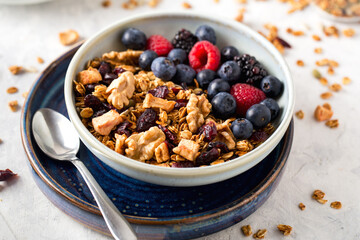 Homemade granola with nuts, seeds and berries in blue plate on table for healthy breakfast