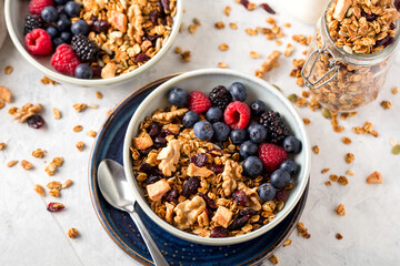 Homemade granola with nuts, seeds and berries in blue plate on table for healthy breakfast, top view