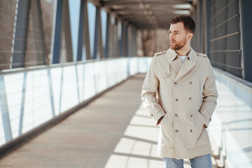 Fototapeta premium Man walks down the street in beige coat