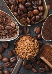 Ground and bean coffee and freeze dried instant coffee granules in various spoons and scoops on black background. Macro