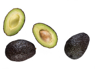 Halved avocado with a stone and two whole ripe avocados cutout on a white background
