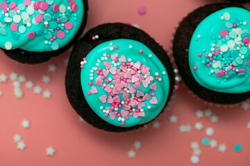 Sugar cupcakes with hearts and frosting close-up on a pastel pink blurred background