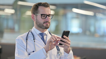Obraz na płótnie Canvas Portrait of Young Male Doctor using Smartphone