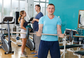 Fototapeta na wymiar Muscular young man practicing with barbell in sport club