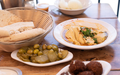 Arabic traditional cuisine.  Hummus on plate with parsley decorate in table pita, olives with pickle, falafel, stuffed dolma, Mediterranean appetizer party idea. on wooden background