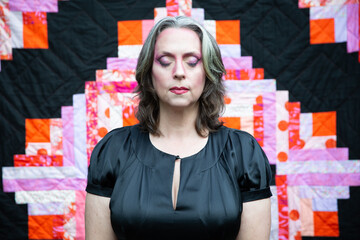 woman in black dress in front of geometric quilt 3