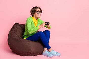 Full size photo of funky concentrated young woman play game hold joystick sit beanbag isolated on...
