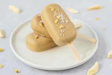 Popsicle with cashews chocolate, mango and coconut on a plate. Sugar, gluten and lactose free.