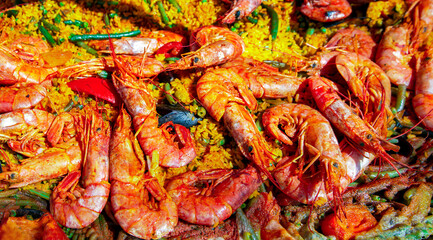 Spanish paella with green beans, large prawns and other seafood cooked in a wok pan on the street.	