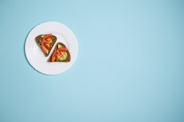 top view of vegetarian sandwich with avocado and tomato on blue background