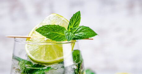Web banner. Refreshing mojito with lime, mint and ice in a glass on a white background close up, free space for text. Cold summer cocktail