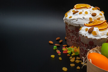 Traditional Easter cakes on black background. Migdal, candied fruits, colorful eggs and raisins, decor. Orthodox treat. Copy space.