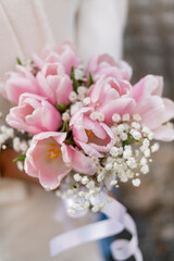 Close-up of a beautiful wedding bouquet of pink white tulips in the hands of the bride
