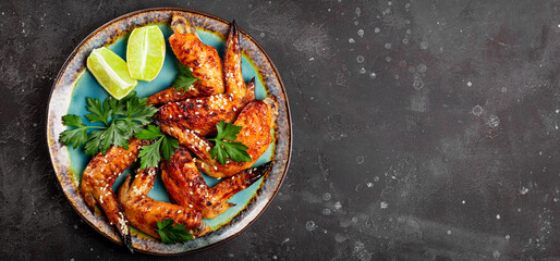 Web banner. Baked chicken wings with sesame seeds, parsley and lime on a plate top view, free space for text