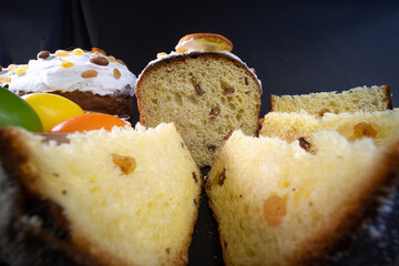 Close-up view. Traditional Easter cake on dark black background. Migdal, candied fruits, raisins, decor colorful eggs. Sectional view, slices, pieces. Orthodox treat.