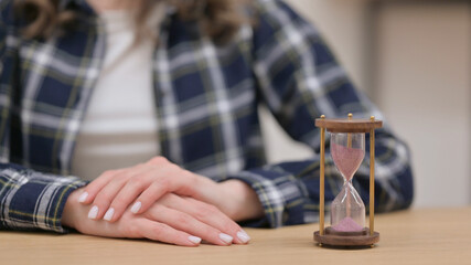 Hourglass Next to Female Hands Waiting Gesture, Close up