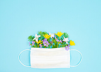 Protective medical mask with natural colorful flowers on a blue background. Flat lay, place for...