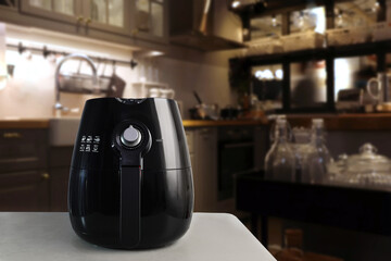 a black deep fryer or oil free fryer , air fryer appliance, is on the grey marble table in the nice...