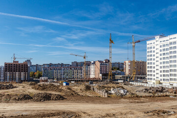 Construction site background. Hoisting cranes and new multi-storey buildings. Industrial...