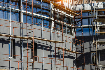 Extensive scaffolding providing platforms for work in progress on a new apartment block,Tall building under construction with scaffolds,Construction Site of New Building