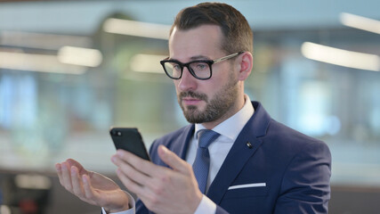 Obraz na płótnie Canvas Businessman Reacting to Financial Loss on Smartphone