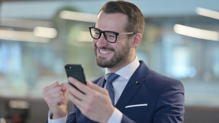 Portrait of Middle Aged Businessman Celebrating on Smartphone