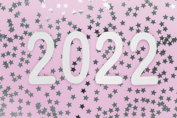 Happy new year wooden numbers 2022 on a festive pink background with sparkles, stars. Greetings, postcard. Calendar, cover