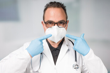 Doctor with medical face mask and medical gloves points to his mask
