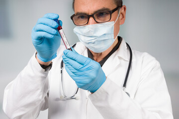 doctor or scientist looks at a positive coronavirus antibody test tube