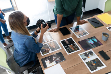 Diverse group of business colleagues wearing masks brainstorming holding camera in meeting room