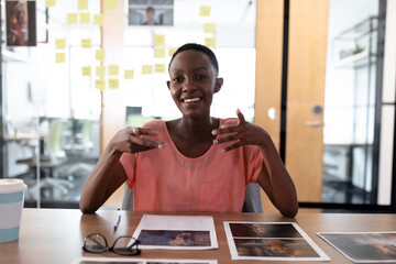 Happy african american businesswoman sitting at desk having video call conversation gesturing