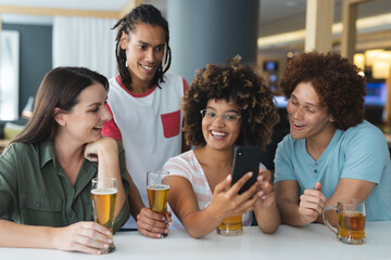 Diverse group of male and female friends looking at smartphone at bar