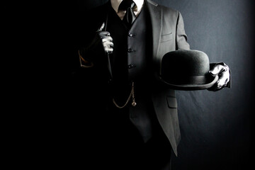 Portrait of Businessman in Dark Suit and Leather Gloves Holding Bowler Hat. Concept of Classic British Gentleman. Retro Fashion and Vintage Style. - obrazy, fototapety, plakaty