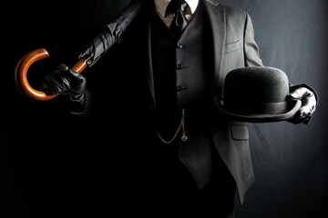 Portrait of Businessman in Dark Suit Holding Umbrella and Bowler Hat. Concept of Classic British...
