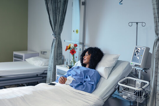 Smiling African American Female Patient Lying In Hospital Bed Looking To Side