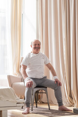 Fototapeta premium Elderly man wearing sport clothing sitting on chair ready for online yoga lesson