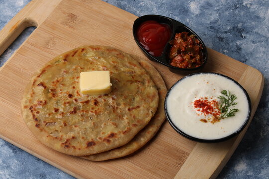 Traditional Indian food Aloo paratha or potato stuffed flat bread. served with pickle  tomato ketchup and curd, 