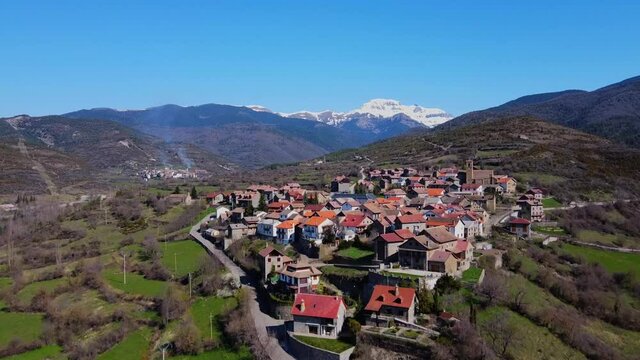 Aerial view of Jasa, typical Mountain Village from Aragon, in the spanish Pyrenees. Snowy mountains in the background with a blue sky