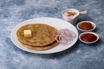 Traditional Indian food Aloo paratha or potato stuffed flat bread. served with pickle  tomato ketchup and curd, butter, onion.