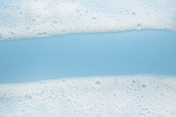 White foam, mousse on a blue background. Frame or border for their foam text. The concept of foaming products, cosmetics or cleaning products.