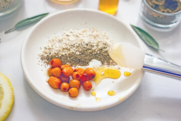 Home cosmetic mask for face skin from natural ingredients of fresh berries, oatmeal, honey, essential oils. Ingredients for making handmade natural cosmetics, flat lay, copy space 