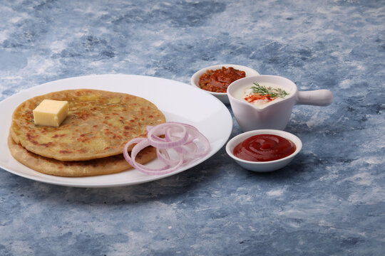 Traditional Indian food Aloo paratha or potato stuffed flat bread. served with pickle  tomato ketchup and curd, butter, onion.