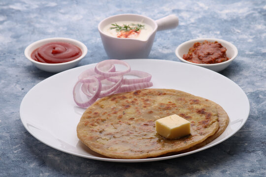 Traditional Indian food Aloo paratha or potato stuffed flat bread. served with pickle  tomato ketchup and curd, butter, onion.