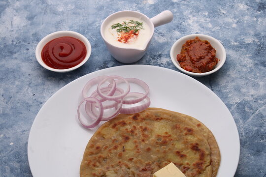 Traditional Indian food Aloo paratha or potato stuffed flat bread. served with pickle  tomato ketchup and curd, butter, onion.