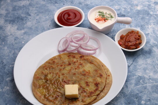 Traditional Indian food Aloo paratha or potato stuffed flat bread. served with pickle  tomato ketchup and curd, butter, onion.