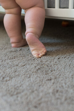 Toddler baby learning to stand and walk; child taking a step revealing sole of foot