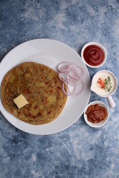 Traditional Indian food Aloo paratha or potato stuffed flat bread. served with pickle  tomato ketchup and curd, butter, onion.