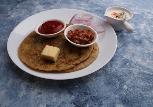 Traditional Indian food Aloo paratha or potato stuffed flat bread. served with pickle  tomato ketchup and curd, butter, onion.