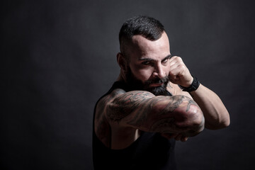 Uomo moro muscoloso, tatuato con la barba, stai un posizione di combattimento pronto all'attacco ,...